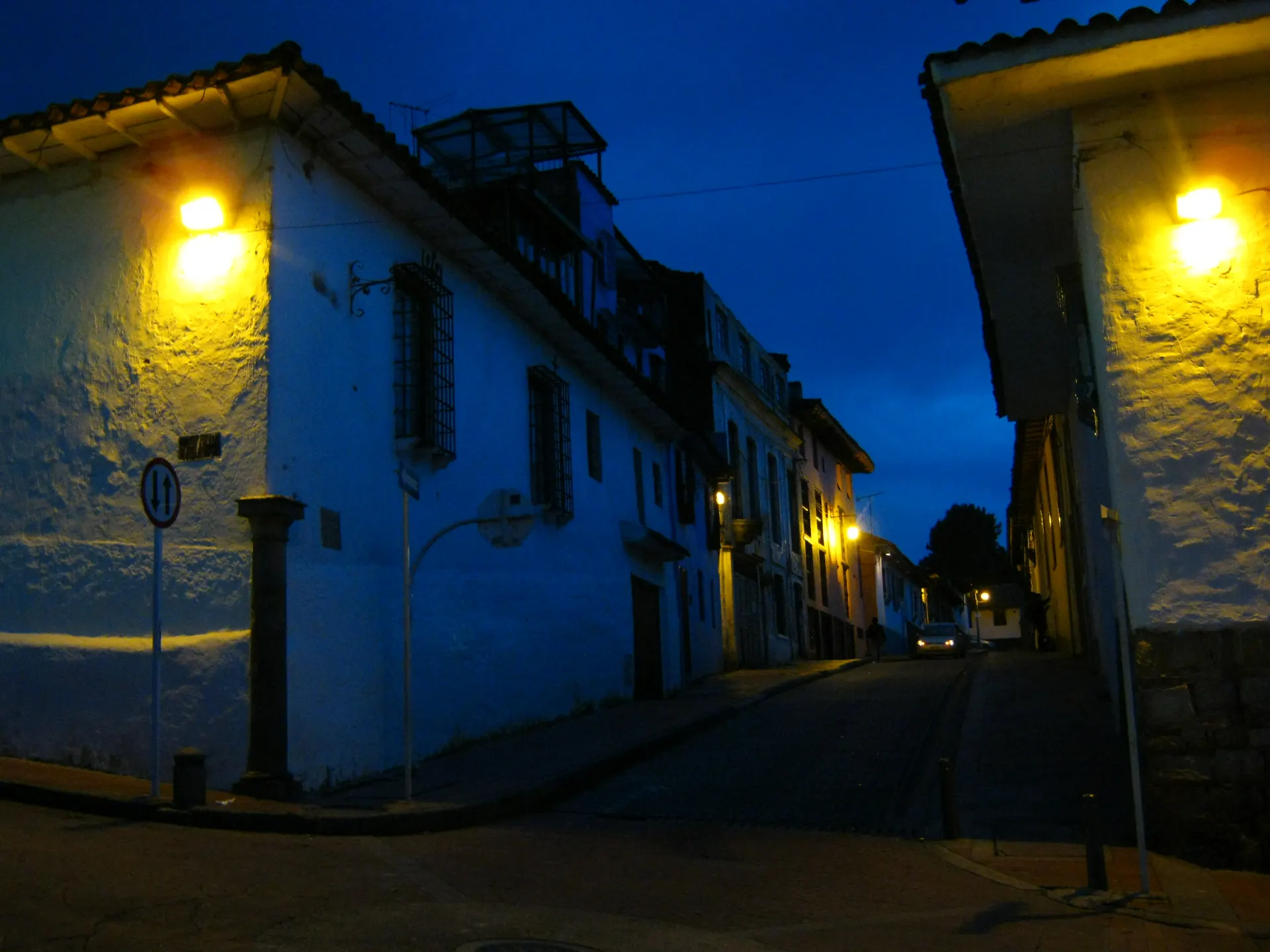 Una calle de La Candelaria, en Bogotá, al anochecer, con los faroles de las casas encendidos